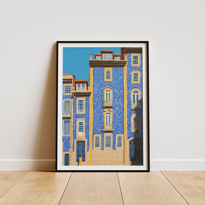 K&ouml;nnte beinhalten: Ein gerahmter Kunstdruck einer Geb&auml;udefassade mit blauen Fliesen und gelben Akzenten. Das Geb&auml;ude hat mehrere Fenster und T&uuml;ren, mit einem klaren blauen Himmel im Hintergrund. Der Druck wird auf einem Holzboden pr&auml;sentiert.