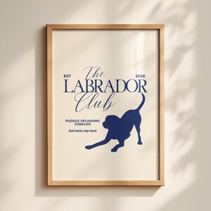 Puede incluir: Un estampado enmarcado con un fondo beige claro y texto y gr&aacute;ficos azul marino. El texto dice "The Labrador Club" con la silueta de un perro labrador. El texto adicional incluye "Puddle splashing forever" y "Eat hard, nap hard".