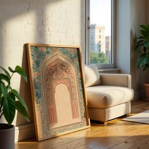 May include: A framed artwork featuring an arched design with floral and geometric patterns in shades of pink, teal, and beige. The artwork is leaning against a white brick wall, with a wooden frame. The scene includes a potted plant and a beige armchair.