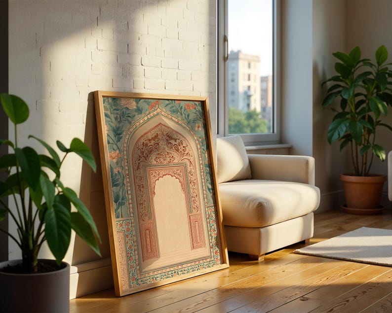 May include: A framed artwork featuring an arched design with floral and geometric patterns in shades of pink, teal, and beige. The artwork is leaning against a white brick wall, with a wooden frame. The scene includes a potted plant and a beige armchair.