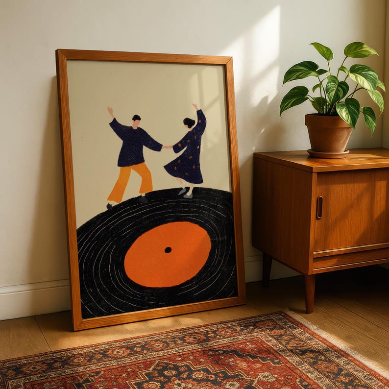 以下が含まれることがあります： レコードの上で踊るカップルを描いた、額入りのアートプリント。 このアートワークは、黒いレコード、オレンジ色の中心、ネイビーとオレンジの人物が特徴のレトロなスタイルです。 フレームは温かみのある茶色です。