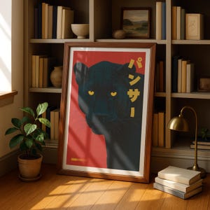 May include: A framed poster featuring a black panther illustration with yellow eyes against a red background. The poster has Japanese text and is in a wooden frame. The image is displayed in a room with bookshelves, a plant, and a lamp.