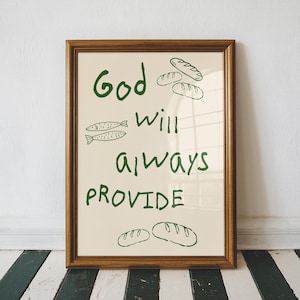 May include: A framed print with the words "God Will Always Provide" in green script. The print features illustrations of bread and fish. The frame is a warm brown colour, and the background is a cream colour.