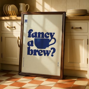May include: Framed poster with the text "fancy a brew?" in navy blue, featuring a stylized coffee cup. The poster has a cream-colored background and a dark brown frame. A small smiley face is in the upper left corner.