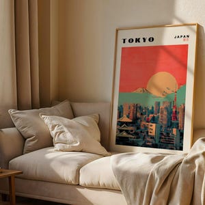 May include: A vintage-style poster with a red, orange, and green color scheme depicting a cityscape with skyscrapers and a mountain in the background. The text "TOKYO" and "JAPAN" is printed in black at the top of the poster.