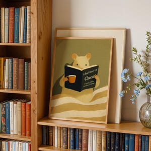 May include: A framed art print depicting a cartoon mouse engrossed in a book titled "A Brief History of Cheese." The mouse holds a mug. The print is displayed on a wooden shelf with books and a vase of flowers.