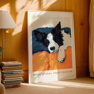 Dog art print of Border Collie with orange background, leaned against wall beside books and lamp – rustic dog lover gift.