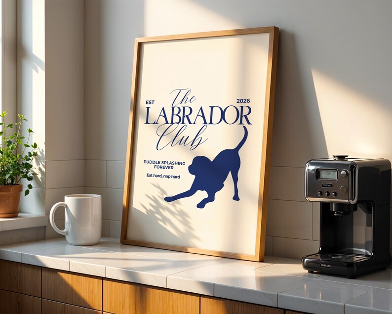 Puede incluir: Un p&oacute;ster enmarcado con el texto "The Labrador Club" y una silueta de perro. El p&oacute;ster est&aacute; en un marco de madera y se exhibe en una encimera junto a una taza blanca y una cafetera. Tambi&eacute;n se incluye el texto "Puddle splashing forever".
