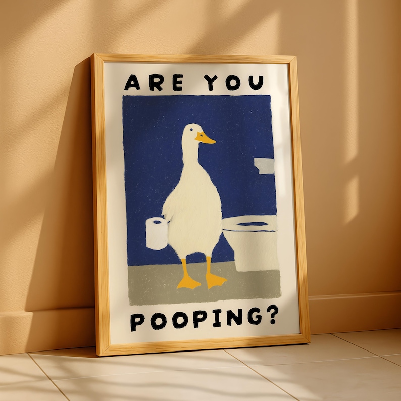 May include: Framed art print featuring a whimsical illustration of a white duck holding toilet paper in a bathroom setting. The artwork has a blue background and the text "ARE YOU POOPING?" in bold, black letters.
