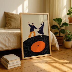 以下が含まれることがあります： レコードの上で踊る2人の人物を描いた、額入りのアートプリント。人物はネイビーとオレンジ色の服を着ており、ベージュの背景に配置されています。レコードは黒色で、オレンジ色の中心があり、天然木で額装されています。