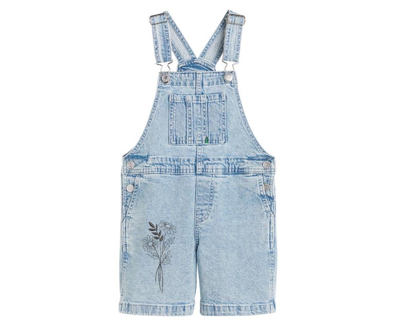 May include: Light blue denim overalls with a floral design on the front. The overalls have adjustable straps and a button closure.