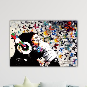 Peut inclure: Impression sur toile représentant un chimpanzé avec un casque, entouré de papillons colorés. L'œuvre utilise des couleurs noires, blanches et vives, créant un effet visuel saisissant. Le thème est la musique et la nature.