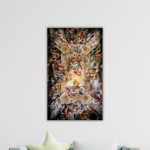 Puede incluir: Una impresión enmarcada de un fresco de techo, que presenta una composición compleja de figuras, nubes y elementos arquitectónicos. La obra de arte es rica en color, con tonos dorados, marrones, azules y rojos. La impresión es rectangular y está montada en una pared blanca.