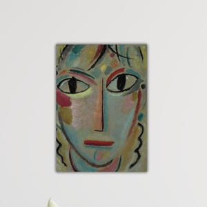 Puede incluir: Pintura de retrato abstracto que presenta un rostro con ojos grandes y oscuros, una boca roja y una nariz larga. La paleta de colores incluye tonos de azul, verde, amarillo y rojo. La obra de arte tiene una apariencia texturizada y está montada en una pared blanca.