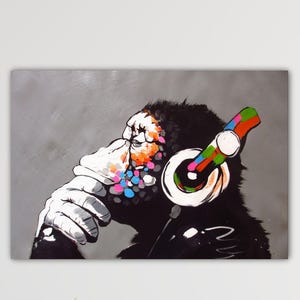 Peut inclure: Une peinture en noir et blanc d'un singe portant un casque coloré. Le singe est assis, le menton sur la main, l'air pensif. L'arrière-plan est gris clair.