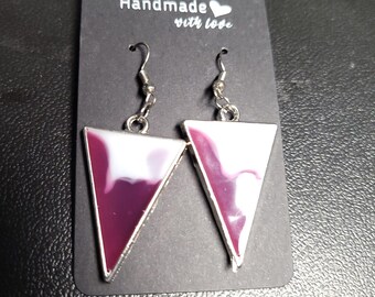Puede incluir: Un par de pendientes hechos a mano con un diseño triangular. Los pendientes presentan un marco plateado y un interior veteado blanco y burdeos. Los pendientes se exhiben en una tarjeta negra con el texto "Handmade with love."