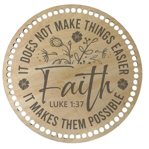 Könnte beinhalten: Eine runde Holzplakette mit einem Zitat über den Glauben. Es lautet: "It does not make things easier, it makes them possible. Faith. Luke 1:37". Die Plakette hat ein florales Design und einen dekorativen Rand.