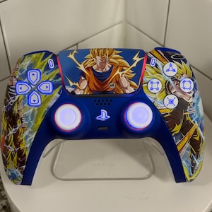Op de afbeelding: Een aangepaste blauwe PlayStation 5-controller met artwork van een personage met stekelig geel haar en oranje kleding. De controller heeft verlichte knoppen en een transparante standaard.