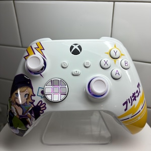 Puede incluir: Mando Xbox blanco con un diseño personalizado con un personaje de dibujos animados y texto japonés. El mando tiene detalles en amarillo y morado, con un diseño de rayo. Los botones son blancos, morados y negros.