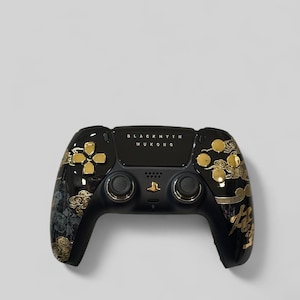 Op de afbeelding: Zwarte en gouden aangepaste videogamecontroller. De controller heeft gouden accenten, waaronder knoppen en decoratieve wolkenontwerpen. De tekst "BLACK MYTH WUKONG" staat op de bovenkant van de controller.