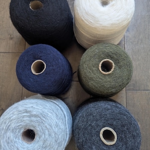 May include: Six spools of yarn in various colors, including black, white, navy blue, dark green, light gray, and dark gray.