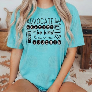 Puede incluir: Una camiseta turquesa con las palabras "ADVOCATE, SUPPORT, ACCEPT, EDUCATE, LOVE, be kind, love" en blanco y negro. La camiseta la lleva una persona sentada sobre una alfombra estampada.