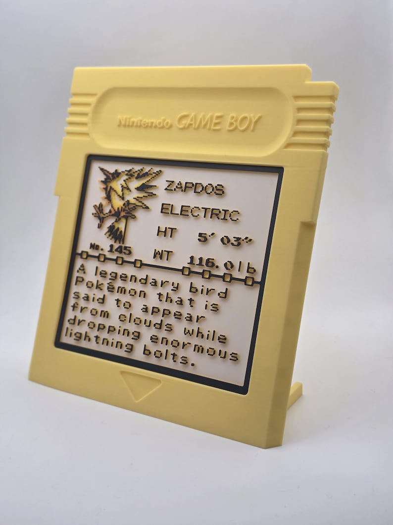 May include: A yellow Game Boy cartridge-shaped display featuring the text "Nintendo GAME BOY." The display includes information about the Pok&eacute;mon Zapdos, including its height of 5' 03" and weight of 116.0 lbs.