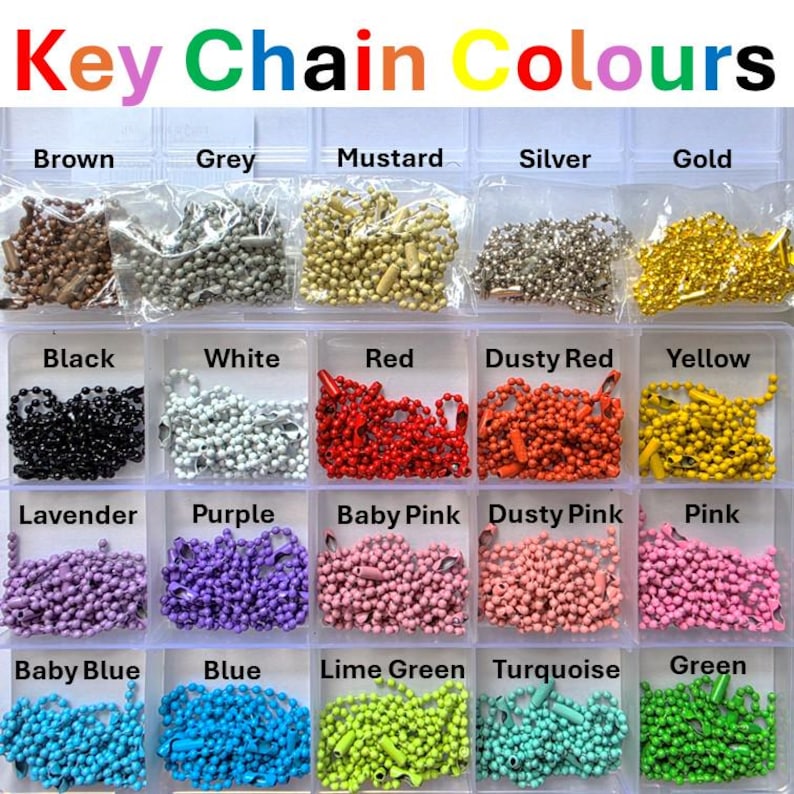 May include: A clear plastic organizer box containing twenty-five individual compartments, each filled with a different colored metal ball chain. The text "Key Chain Colours" appears at the top, followed by labels for each color including brown, grey, mustard, silver, gold, black, white, red, dusty red, yellow, lavender, purple, baby pink, dusty pink, pink, baby blue, blue, lime green, turquoise, and green.