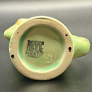 May include: A vintage Wade Heath England ceramic creamer. The creamer is light green with a darker green rim and handle. The bottom of the creamer has the Wade Heath England stamp and the number 151.