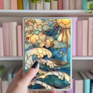 Puede incluir: Una funda transparente para teléfono con un diseño de vitral que presenta un sol, nubes y olas en tonos azules, dorados y blancos.