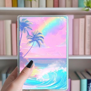 May include: A clear phone case with a holographic design featuring a pink and blue sunset with palm trees and ocean waves.