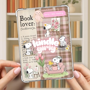 May include: A clear Kindle case with a brown plaid pattern and Snoopy illustrations. The case features the text "Book lover" and "Kindle girly", along with Snoopy reading, painting, and relaxing. A pink bunny and the text "sorry I was reading" are also included.