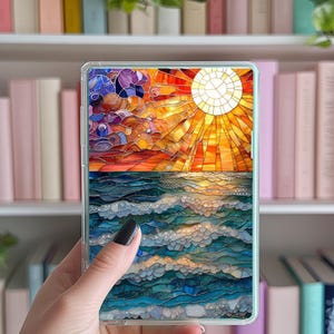 May include: A stained glass phone case with a sunset and ocean scene. The sun is yellow and orange, the sky is red and orange, and the ocean is blue and green.