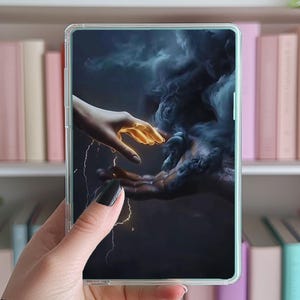 May include: A phone case with a dark blue background featuring two hands reaching towards each other. One hand is glowing gold and the other is dark with smoke swirling around it. Lightning bolts are visible in the background.