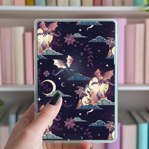 May include: A clear phone case with a repeating pattern of purple and blue dragons flying in a starry night sky with clouds and crescent moons.