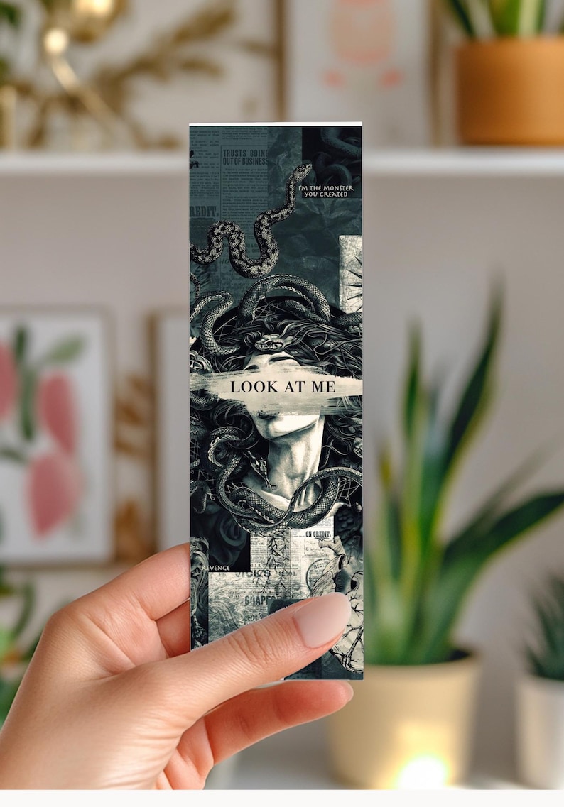 May include: A bookmark featuring a Medusa-like figure with snakes and the text "LOOK AT ME". The design is in grayscale with newspaper-style backgrounds. The bookmark is rectangular and held by a hand.
