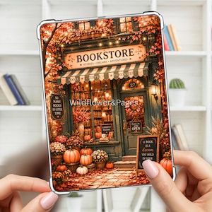 Può includere: Una custodia protettiva trasparente per tablet con un'illustrazione stampata di una libreria decorata con foglie autunnali e zucche. Il testo recita BOOKSTORE, STORIES, DREAMS, ADVENTURES, Wildflower&Pages, 50 MANY BOOKS SO LITTLE TIME e A BOOK IS A dream YOU HOLD IN YOUR.