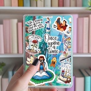 Könnte beinhalten: Eine transparente Handyhülle mit verschiedenen bunten Stickern, die Figuren und Szenen aus dem Disney-Film Die Schöne und das Biest zeigen. Die Sticker beinhalten Belle, das Biest, die verzauberte Rose und das Schloss. Der Text "Es war einmal" ist ebenfalls auf der Hülle zu sehen.