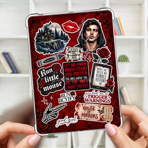 Puede incluir: Una funda para tableta con fondo rojo oscuro que presenta varias pegatinas, incluyendo una mansión gótica, una persona con capucha, rosas rojas, una mano esquelética y textos como "Run little mouse", "House of Mirrors" y "When I die delete my Kindle history".