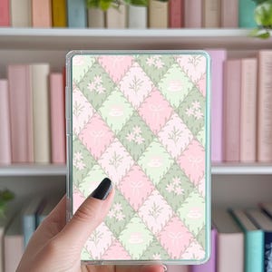 May include: A clear plastic case with a pink and green floral pattern. The pattern features small flowers, leaves, and teacups.