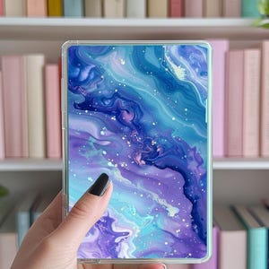 May include: A clear phone case with a galaxy-like design featuring swirling blue, purple, and white colours with silver glitter accents.