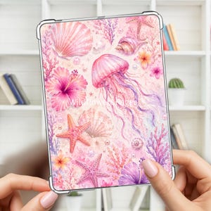 Puede incluir: Una funda transparente para tableta con un vibrante estampado de acuarela de medusas rosas, estrellas de mar, conchas, corales y flores de hibisco. El diseño incluye perlas dispersas y el texto Wildflower&Pages en blanco en el centro.