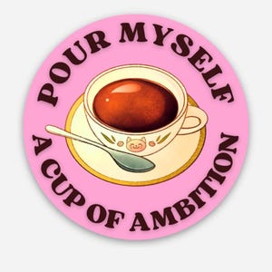 May include: A pink circle sticker with the text "Pour Myself A Cup Of Ambition" in brown text. The sticker features a cartoon illustration of a cup of coffee with a saucer.