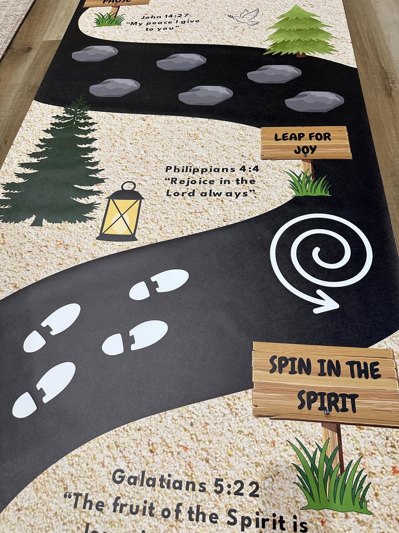 May include: A black and tan pathway featuring white footprints, rocks, and trees. The pathway includes Bible verses such as "John 14:27", "Philippians 4:4", and "Galatians 5:22". Signs read "Leap for Joy" and "Spin in the Spirit".