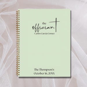 May include: A light green spiral bound notebook with the text "the officiant" in black cursive writing. Below the text is "Carlos Garcia Gomez" in black text. The bottom of the notebook has the text "The Thompson's October 16, 20XX" in black text.