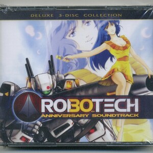 Peut inclure: Boîtier de CD scellé pour la bande originale de l'anniversaire de Robotech. La couverture présente une femme en robe jaune, un robot futuriste et le texte "ROBOTECH ANNIVERSARY SOUNDTRACK". L'emballage indique "DELUXE 3-DISC COLLECTION".