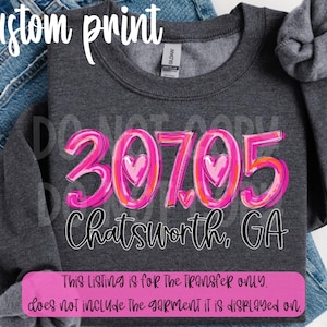 Puede incluir: Una sudadera gris oscuro con el número "30705" en rosa y naranja, con un corazón en el cero. Debajo, "Chatsworth, GA" en escritura negra. El texto "custom print" está en la parte superior.