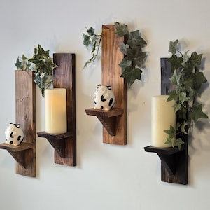 May include: Three rustic wooden wall shelves with a candle holder and a small pig figurine on each. The shelves are stained in a dark brown color and have a simple design. The shelves are decorated with green ivy.