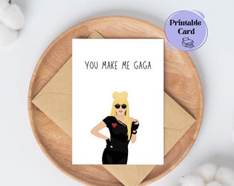 May include: Printable card with a cartoon illustration of Lady Gaga wearing sunglasses and a black outfit. The text on the card reads "You make me Gaga."