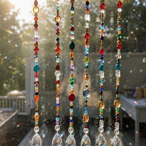May include: Six vertical hanging strands featuring a variety of multicolored glass and crystal beads in assorted shapes and sizes. Each strand terminates in a clear, faceted, teardrop-shaped crystal prism that catches and refracts sunlight.